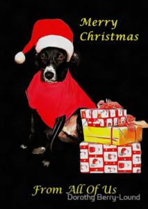 A greeting card featuring a black dog with a red tshirt and a santa hat sitting next to a pile of wrapped gifts. As the words Happy Christmas From All Of Us